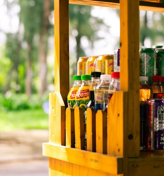 Vibrant wooden beverage stand with colorful bottles in a sunny outdoor setting.