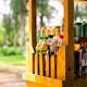 Vibrant wooden beverage stand with colorful bottles in a sunny outdoor setting.
